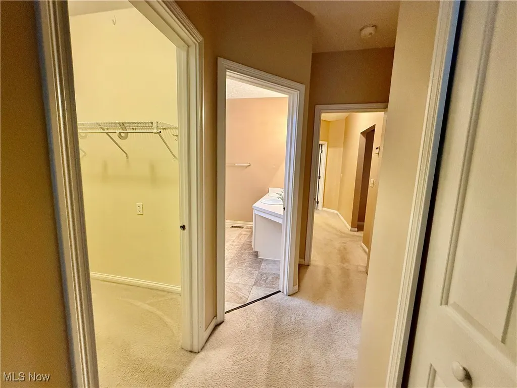 Hallway featuring light colored carpet and baseboards