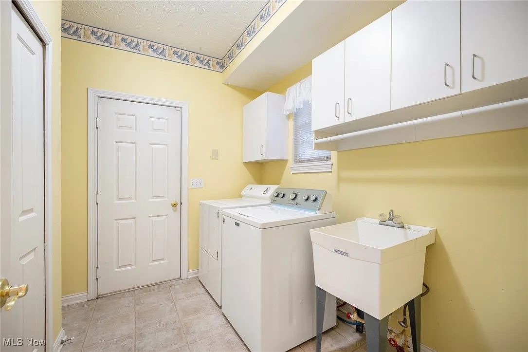 Laundry area featuring cabinet space, separate washer and dryer, and light tile patterned floors
