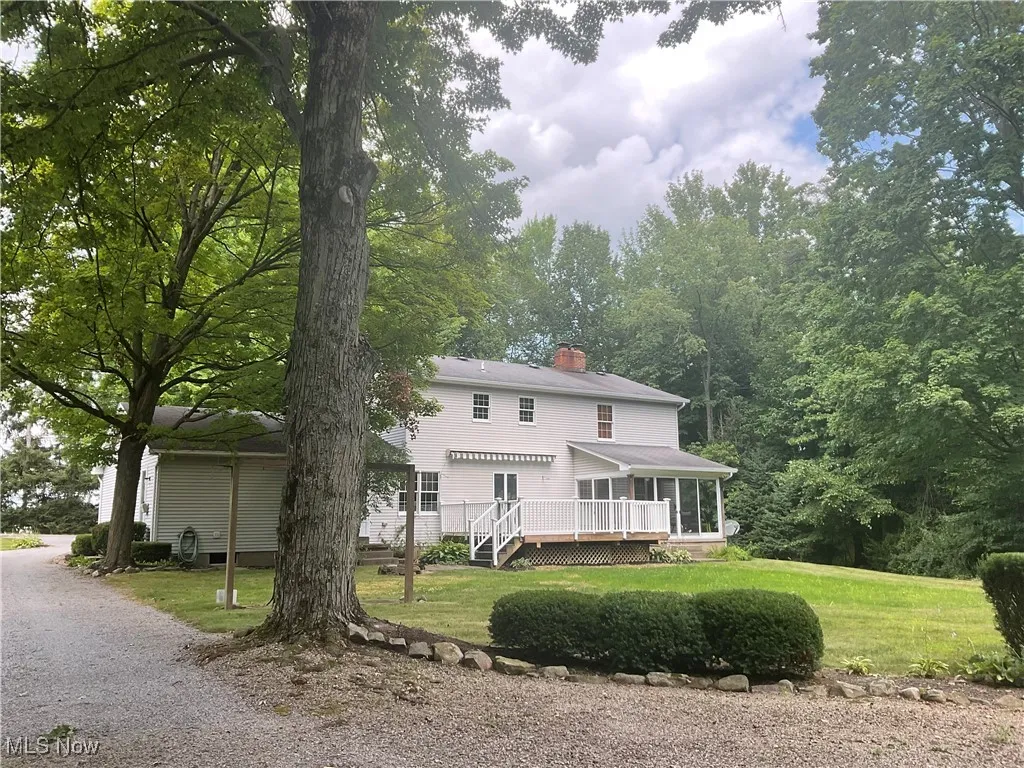 View of front of property with a deck, a chimney, a front yard, and a sunroom