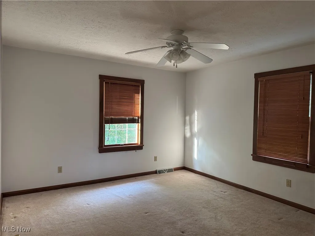 Carpeted spare room with ceiling fan and a textured ceiling