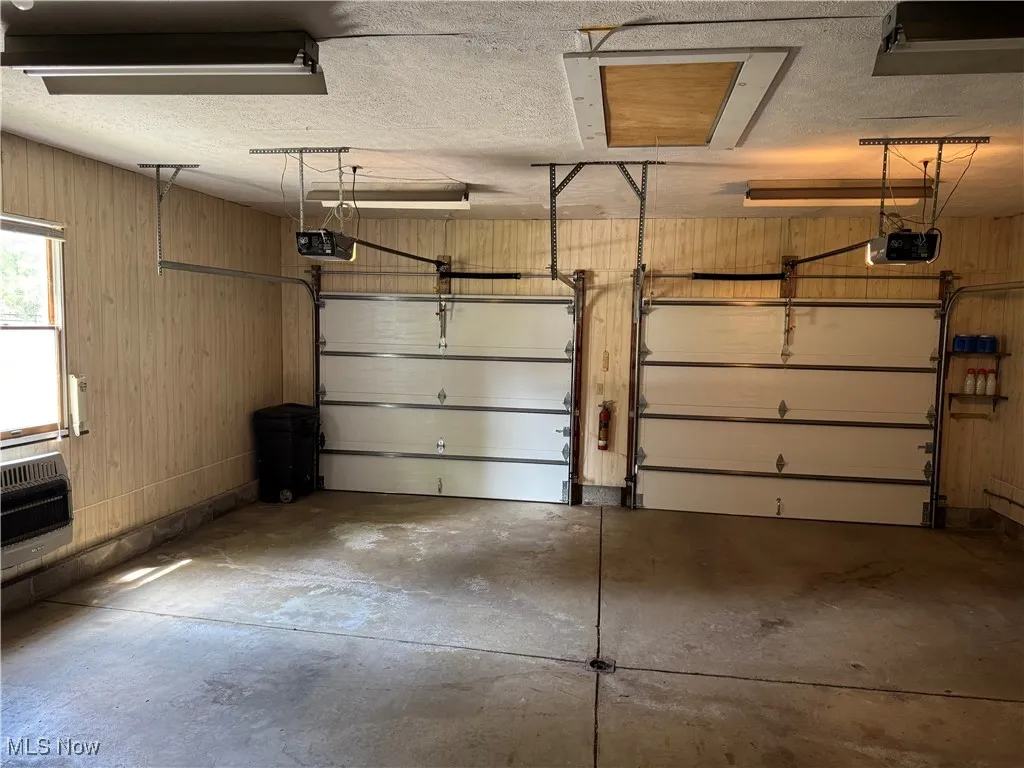 Attached 2 car Garage featuring heating unit, wooden walls, and a garage door opener