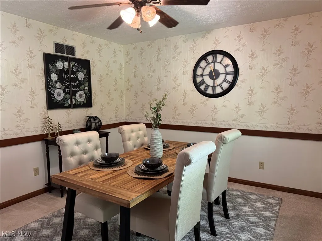 Dining space with a ceiling fan, a textured ceiling, and carpet flooring