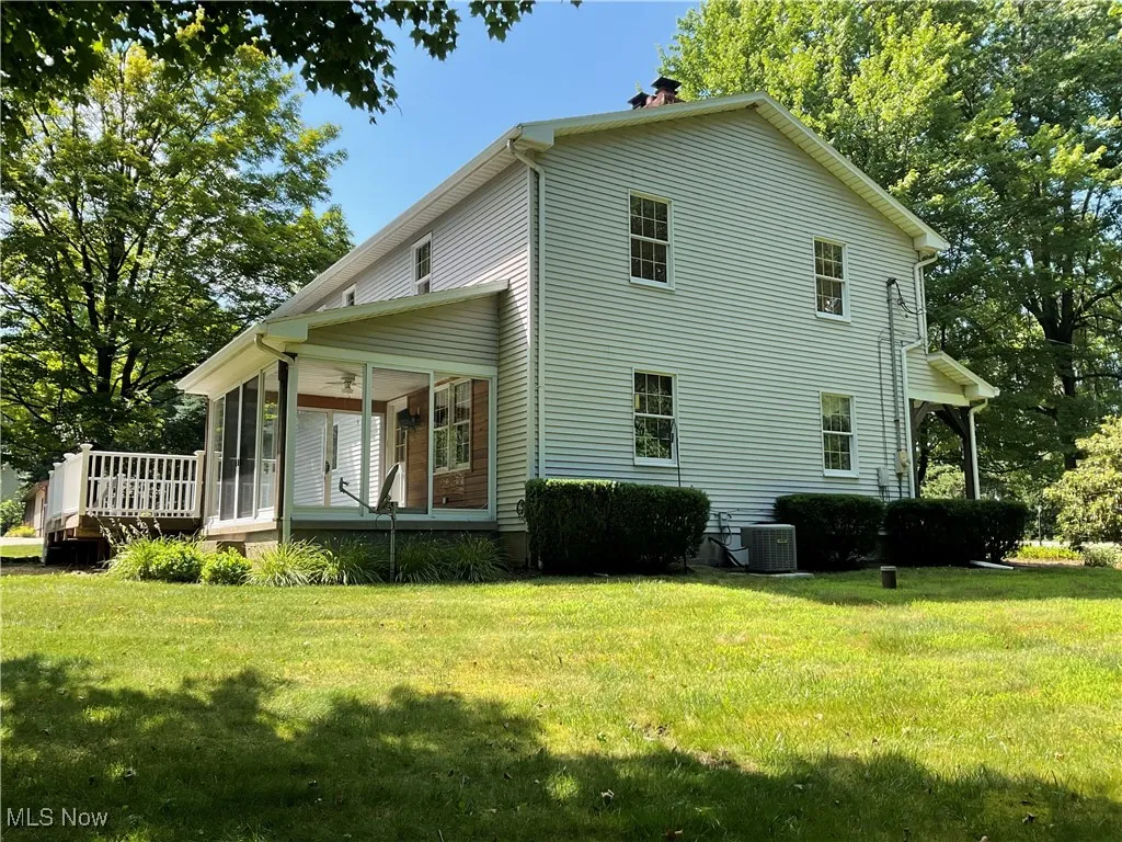 Rear view of property featuring a sunroom, a chimney, and a yard