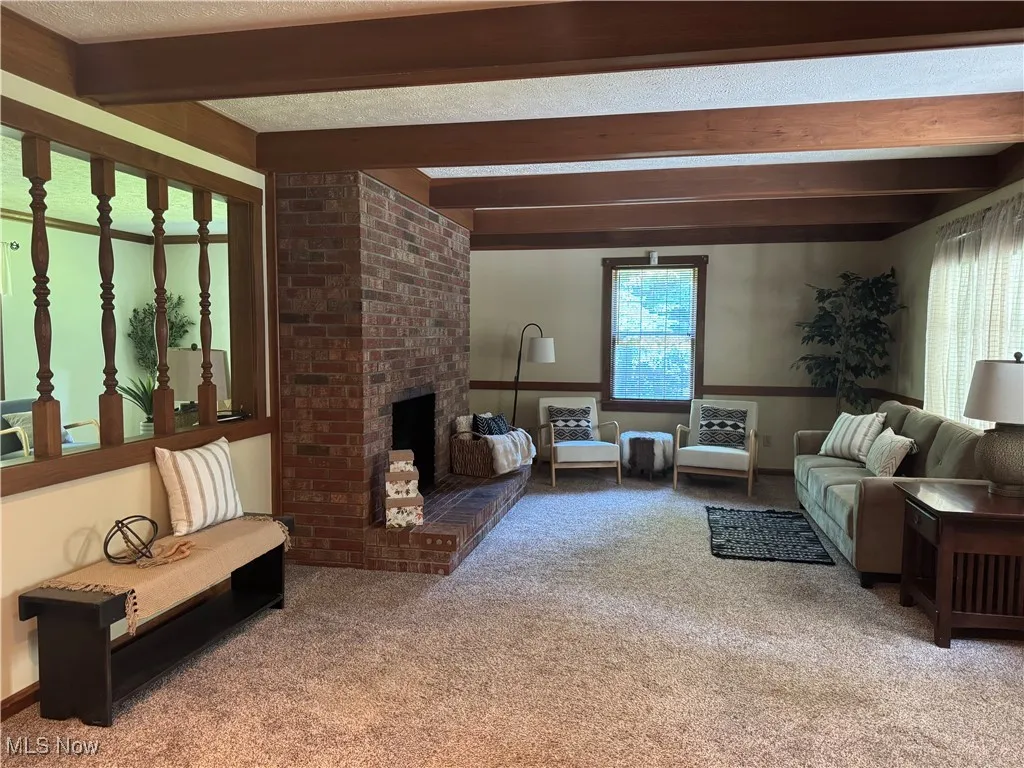 1st floor Family room with beam ceiling, healthy amount of natural light, carpet floors, and a fireplace
