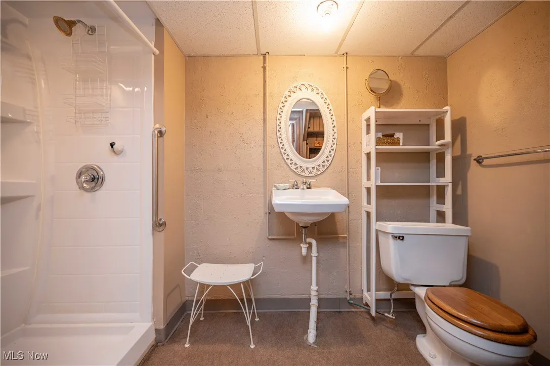Bathroom with a walk-in shower and a textured wall