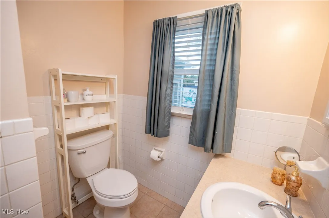 Bathroom with tile walls, tile patterned flooring, and vanity