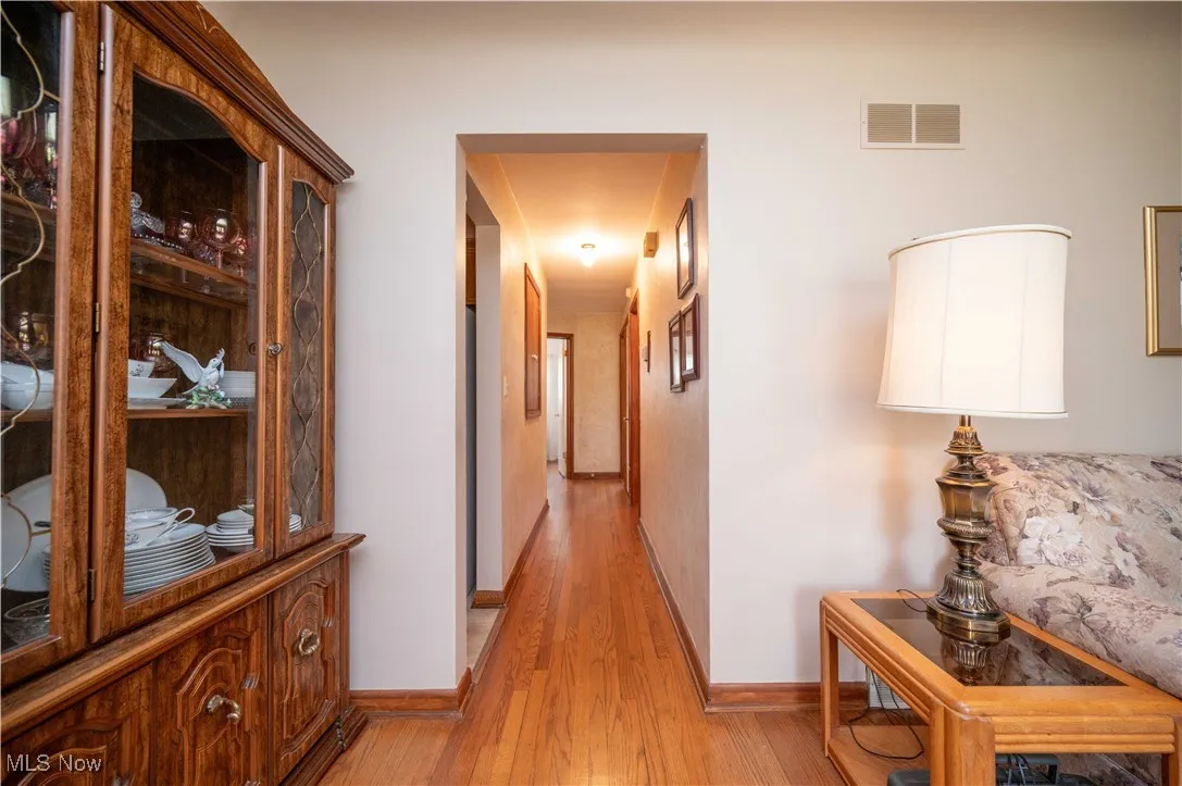 View of hall from living room with light wood-type flooring and baseboards