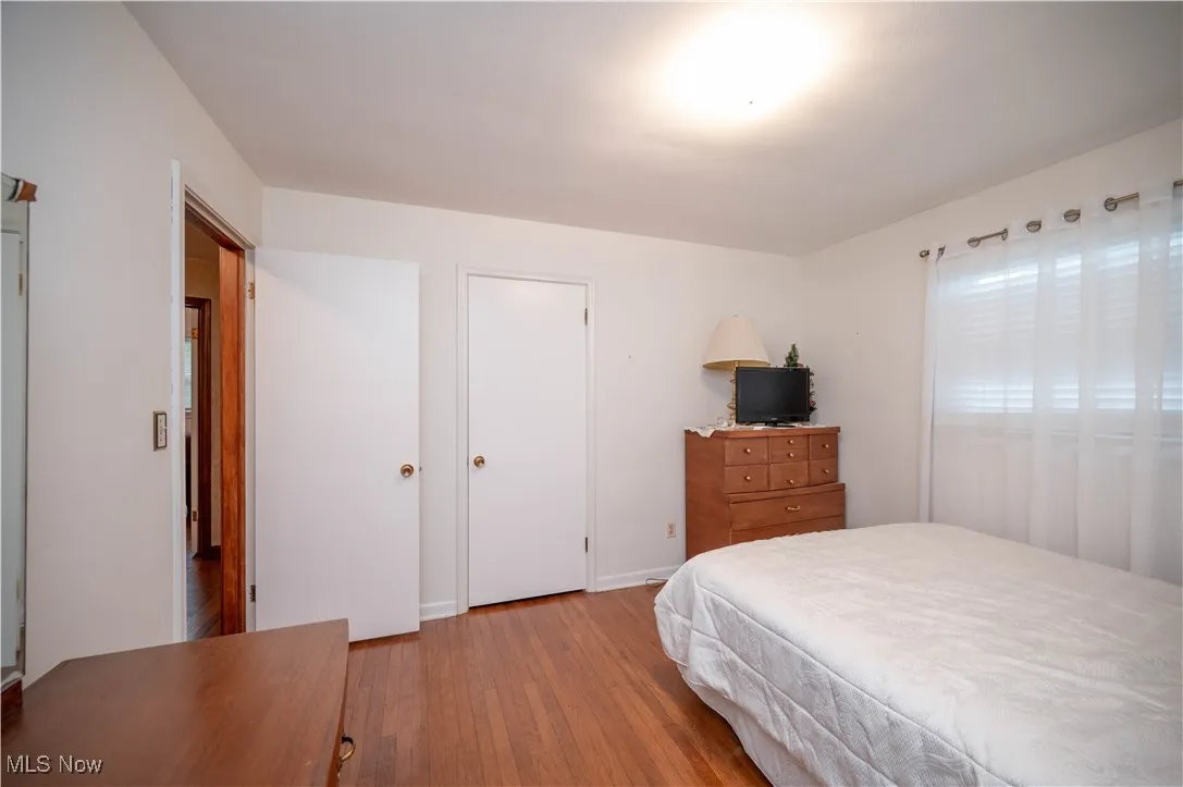 Bedroom with wood finished floors and closet