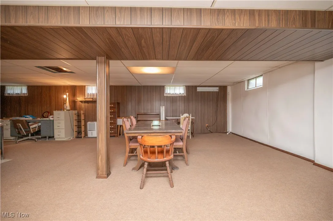 Carpeted area featuring wood walls