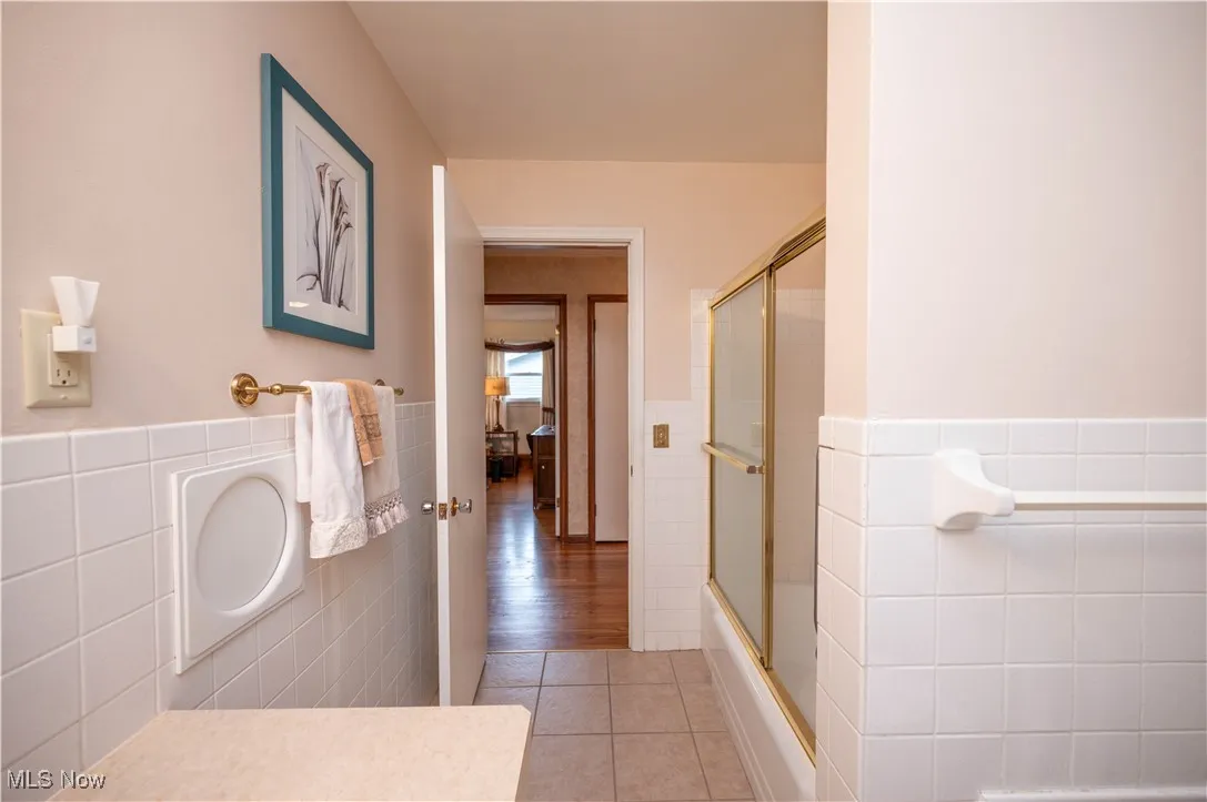 Bathroom featuring tile walls, tile patterned floors, and a laundry shoot