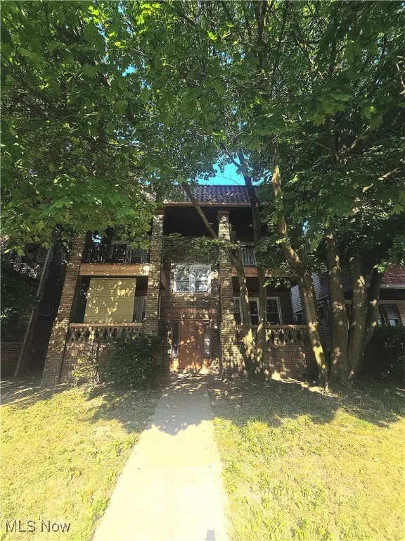 View of front facade featuring a front lawn and a balcony