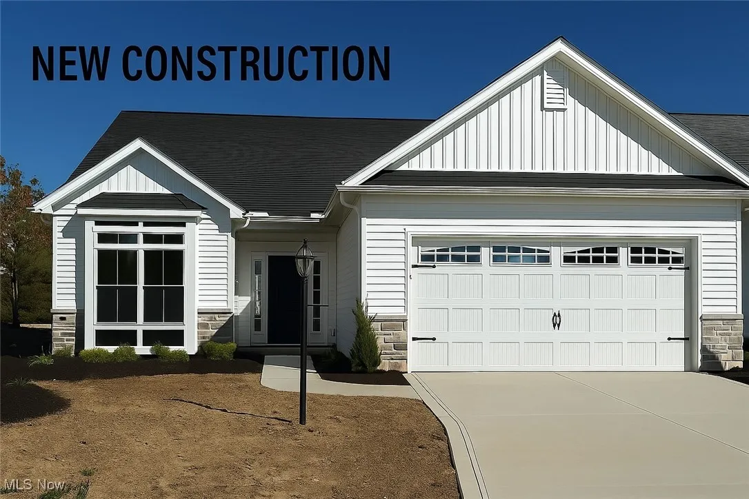View of front of home with stone siding, board and batten siding, an attached garage, and concrete driveway