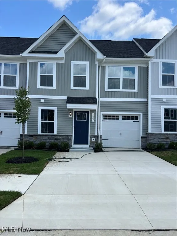 Craftsman-style home with stone siding, driveway, an attached garage, and board and batten siding