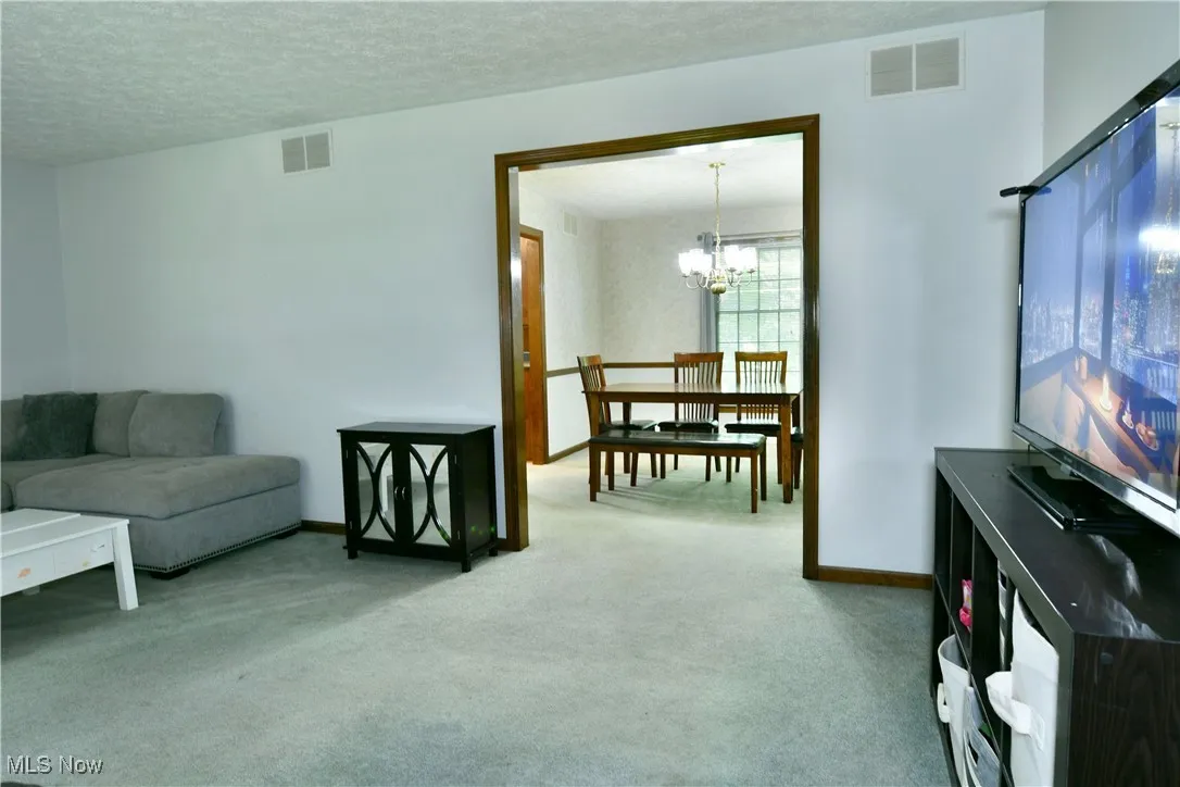 Living area featuring carpet, a chandelier, and a textured ceiling