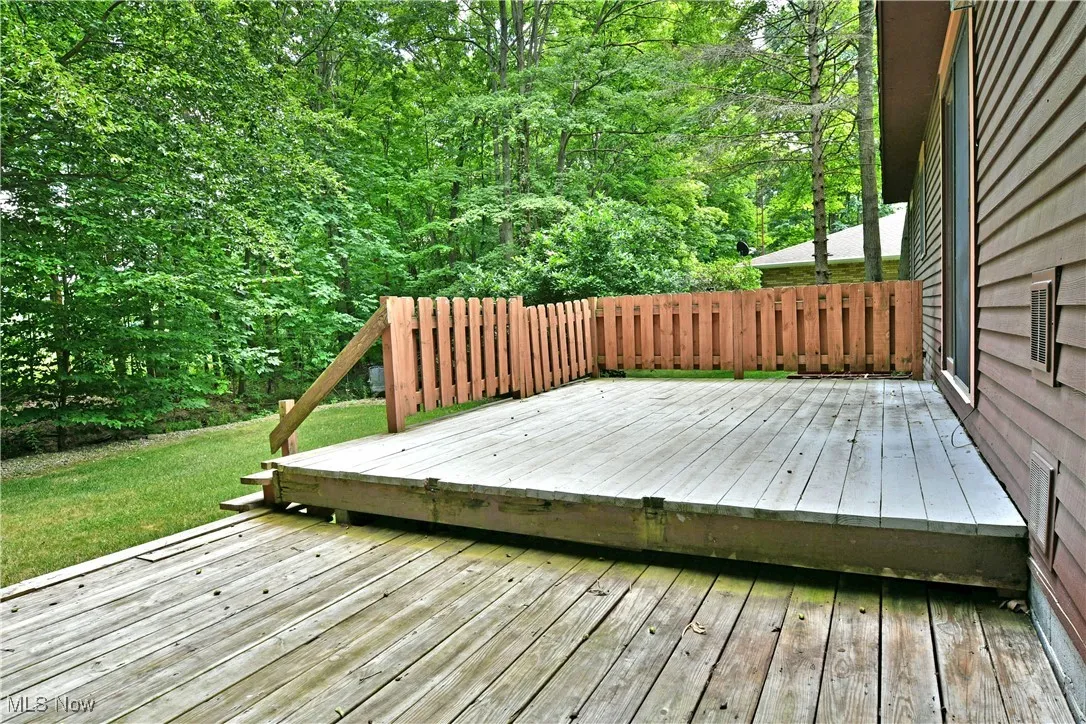Wooden terrace featuring a lawn and a wooded view