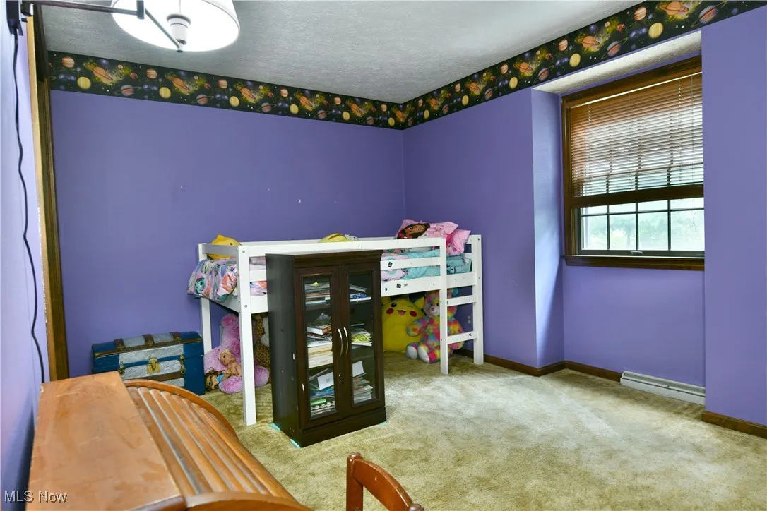 Bedroom featuring carpet, baseboard heating, and a textured ceiling