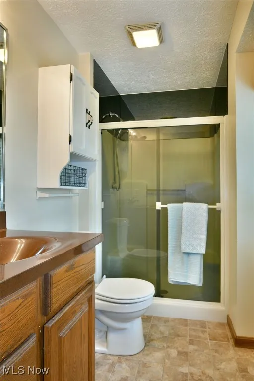 Bathroom featuring vanity, a stall shower, and a textured ceiling