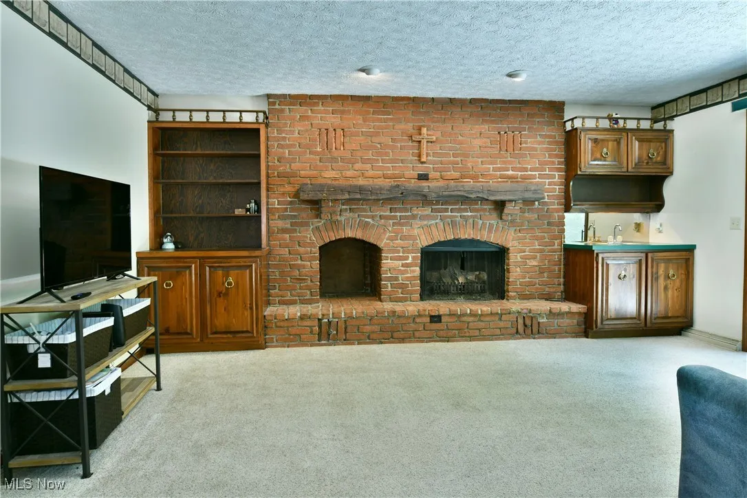 Carpeted living area featuring a textured ceiling and a brick fireplace
