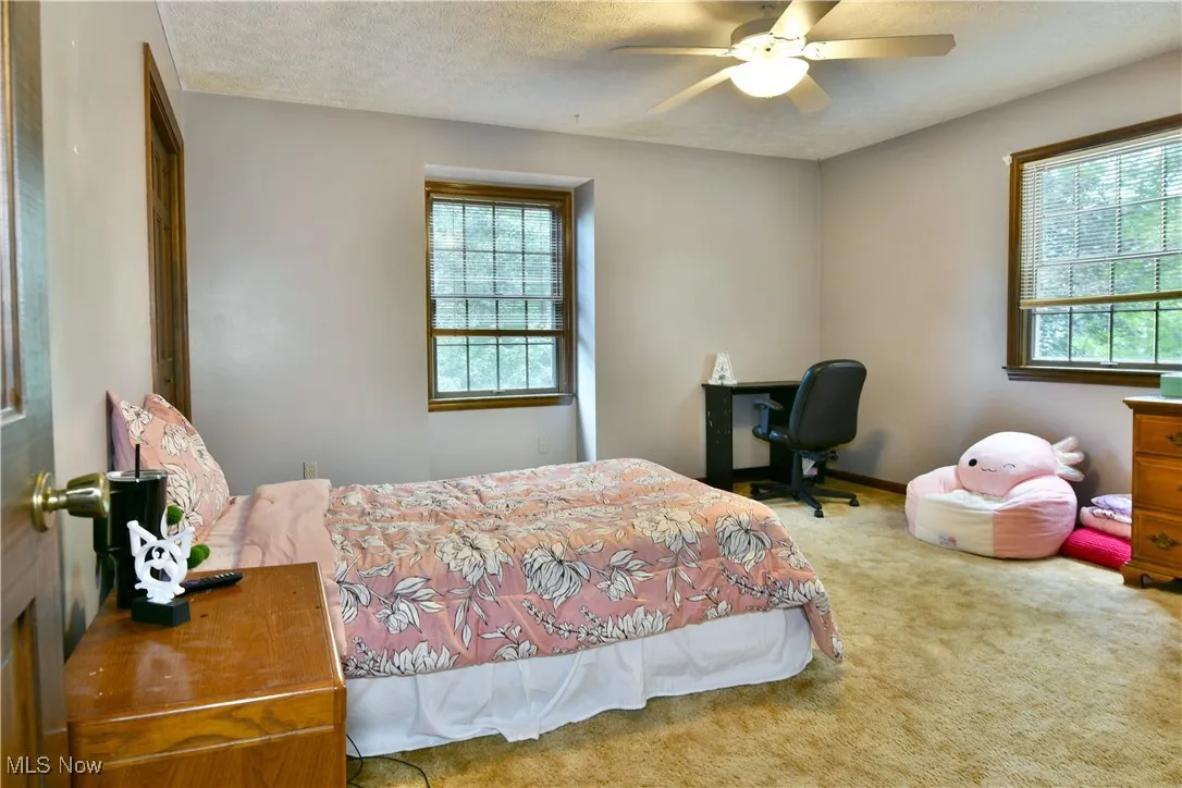 Carpeted bedroom with ceiling fan and a textured ceiling