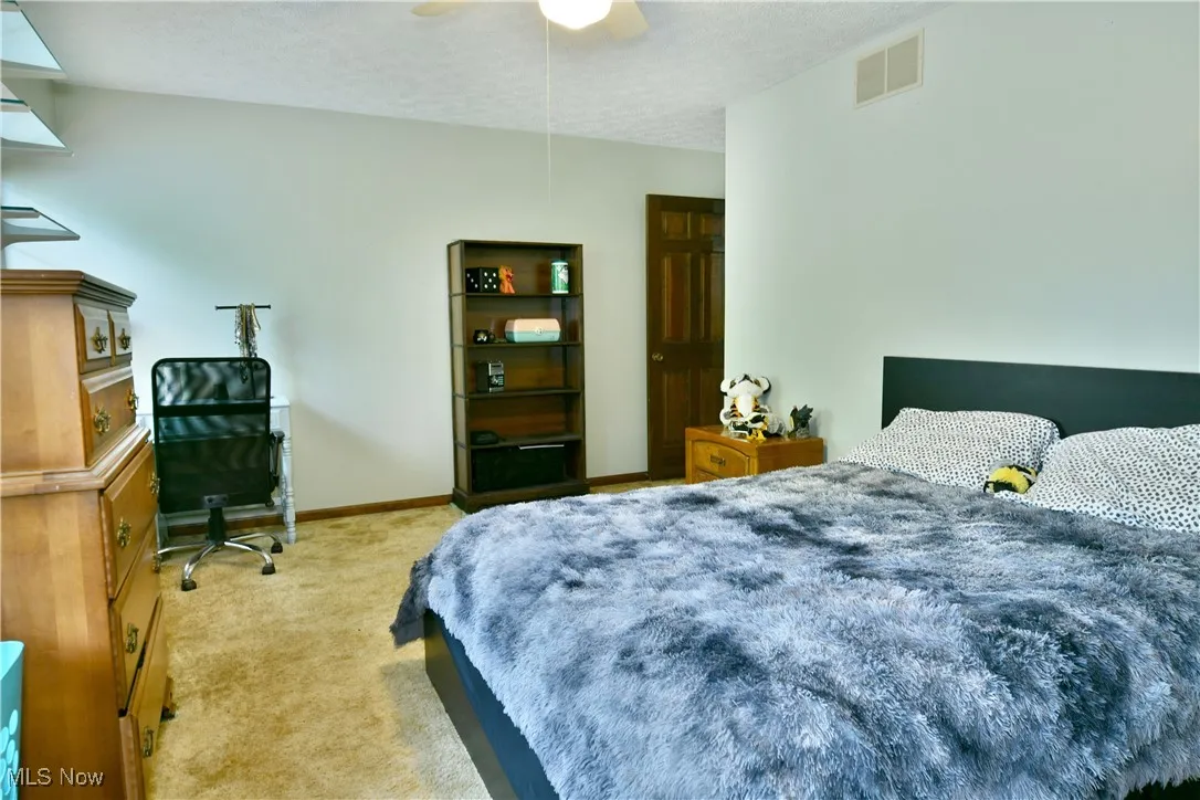 Bedroom featuring light colored carpet, ceiling fan, and a textured ceiling
