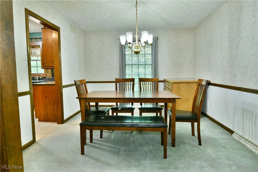 Dining space featuring a chandelier, a textured ceiling, and light colored carpet