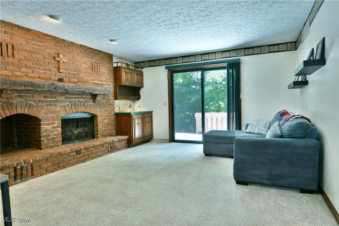 Living room featuring light colored carpet, a fireplace, and a textured ceiling