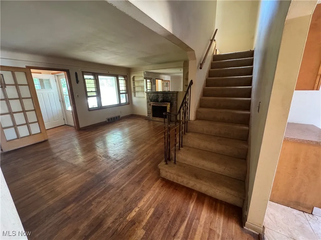 Stairway with hardwood / wood-style flooring and a fireplace
