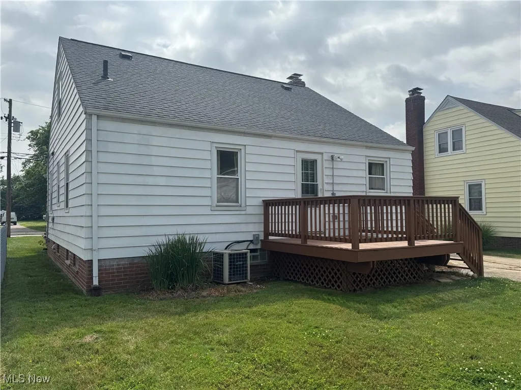 Back of house with a shingled roof, a deck, a yard, and crawl space
