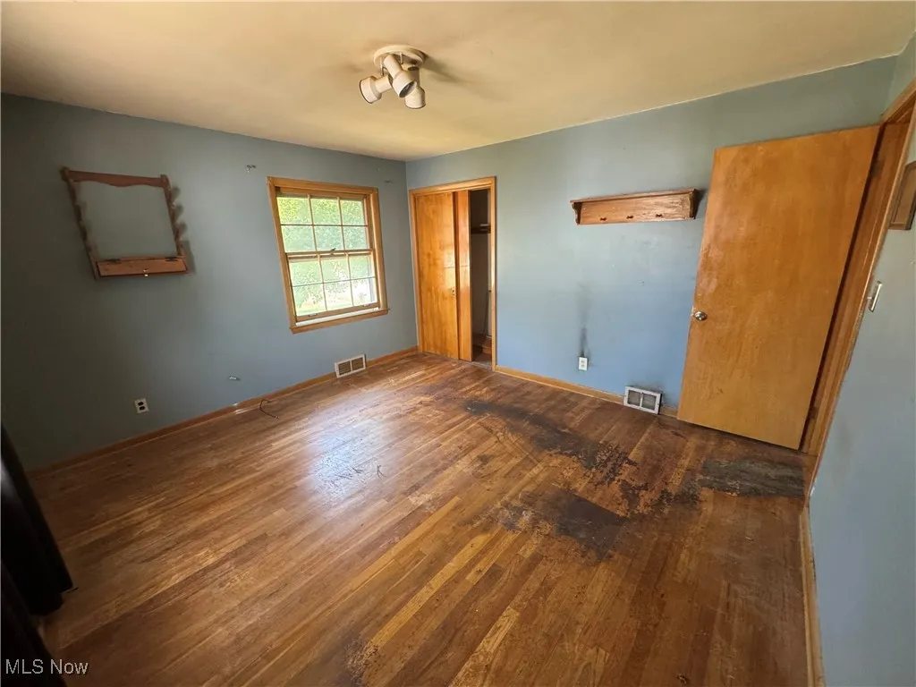 Unfurnished bedroom with wood finished floors and a closet