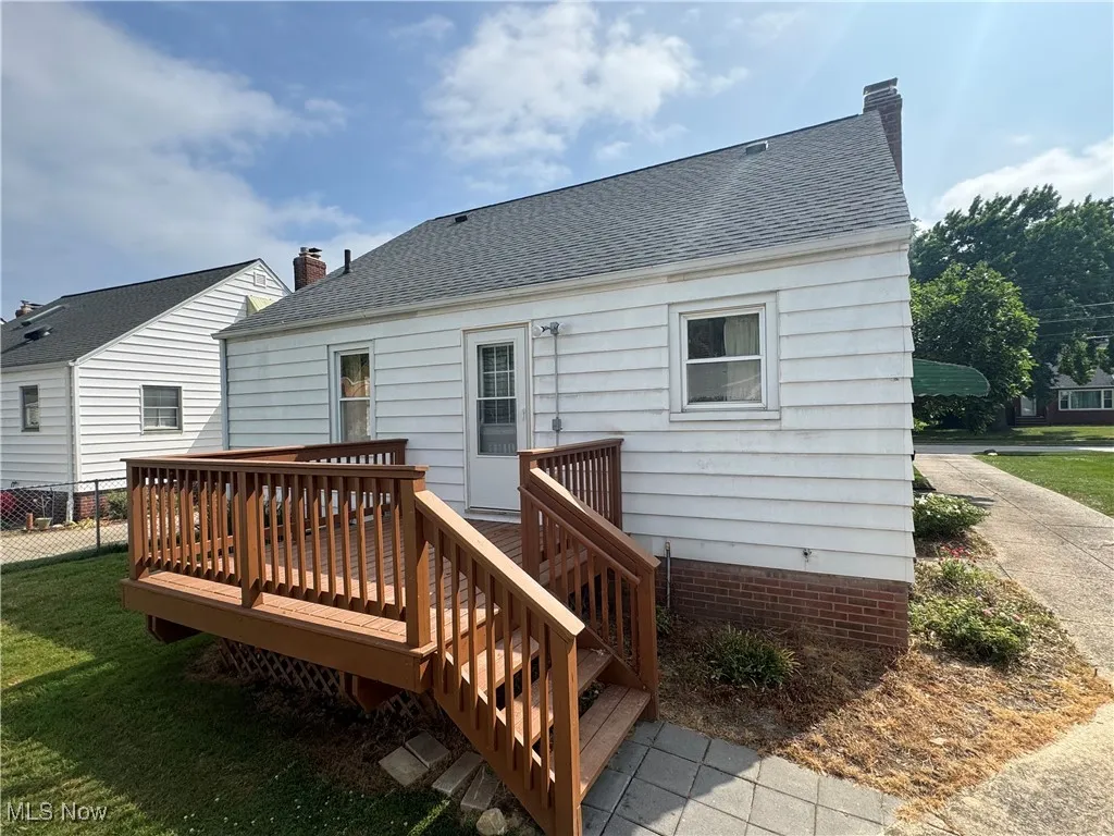 Back of house with a shingled roof, a wooden deck, and a chimney