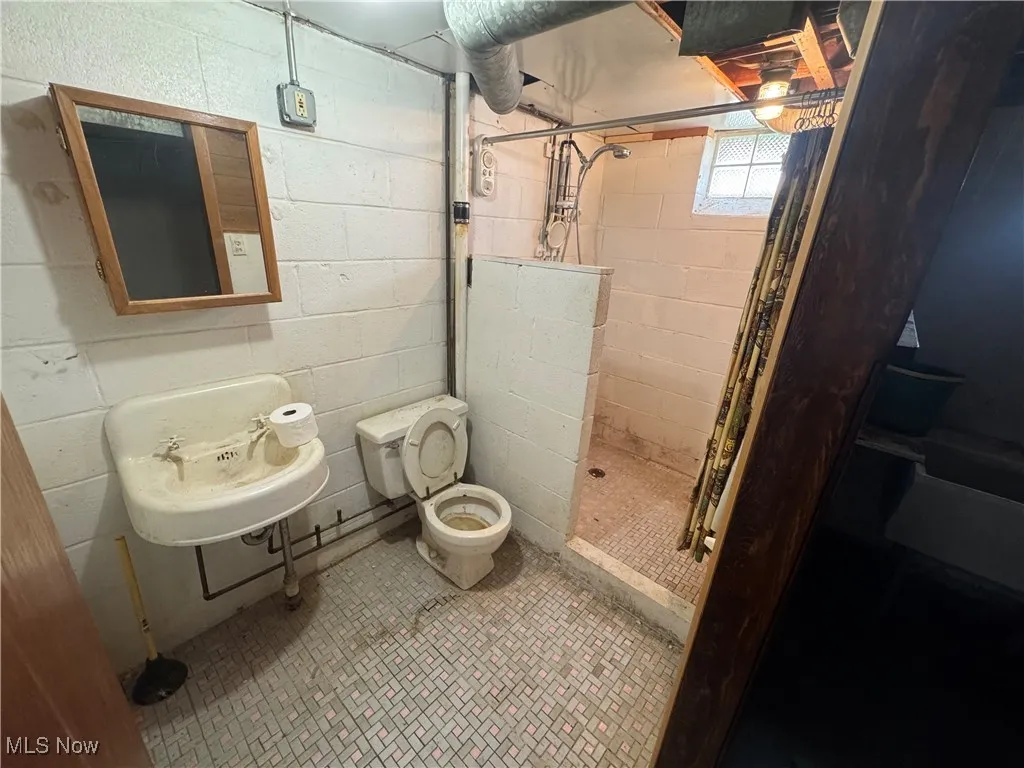 Full bath with a stall shower and concrete block wall