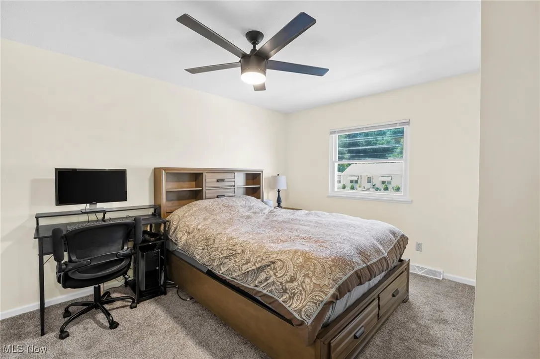 Carpeted bedroom with a desk and a ceiling fan