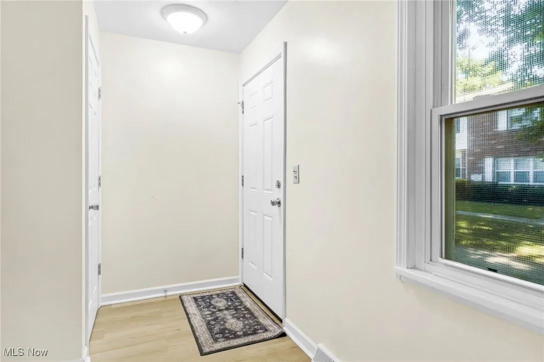 Doorway with light wood-type flooring and baseboards