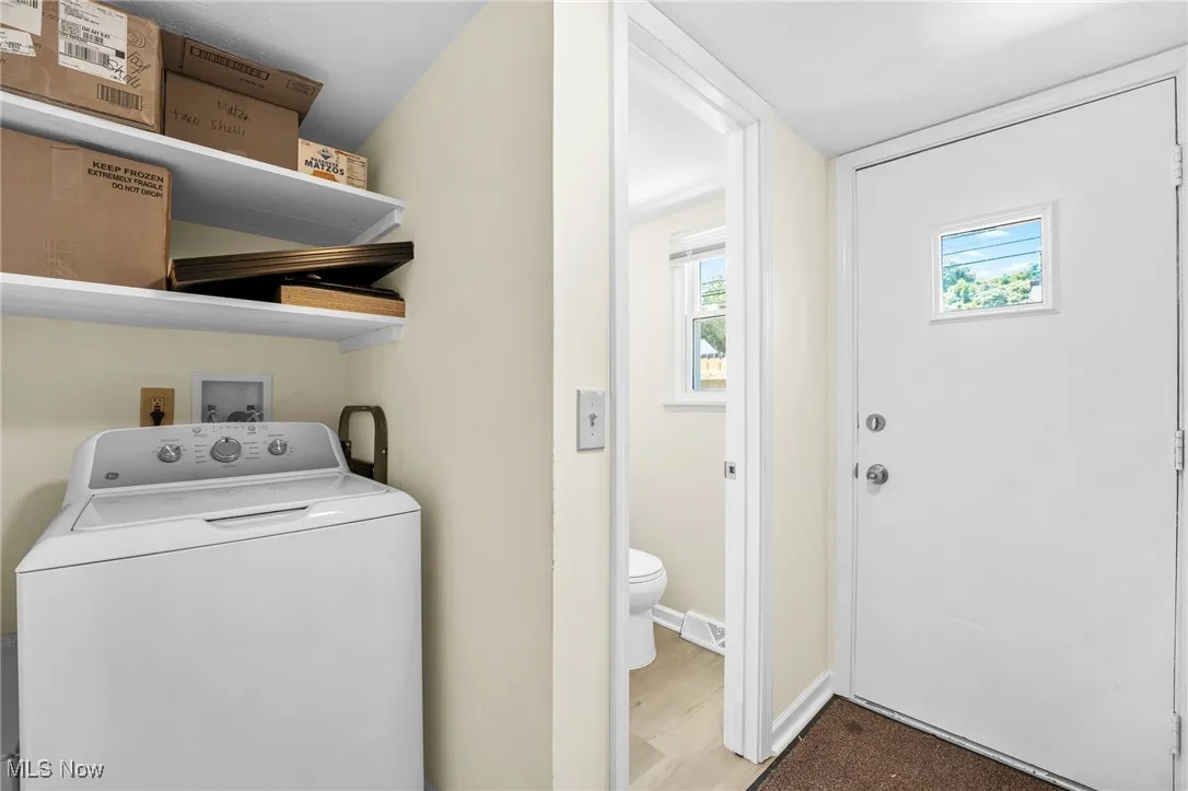Washroom featuring washer / clothes dryer, plenty of natural light, and wood finished floors