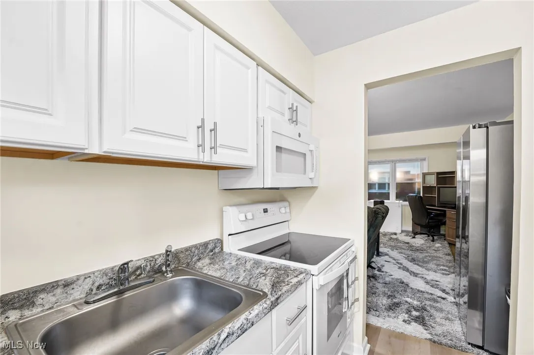 Kitchen with white range with electric cooktop, freestanding refrigerator, white cabinetry, wood finished floors, and a desk