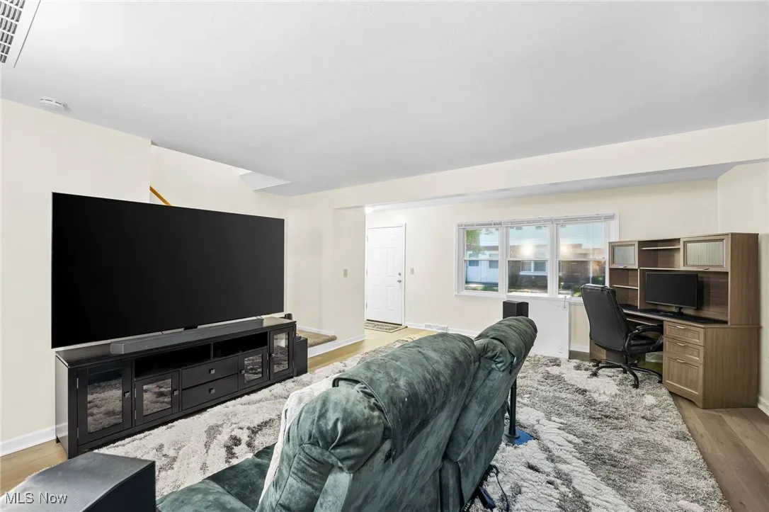 Living area featuring light wood finished floors, a desk, and stairway