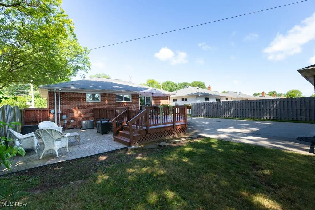 Rear view of property with a patio area, a fenced backyard, brick siding, and a deck