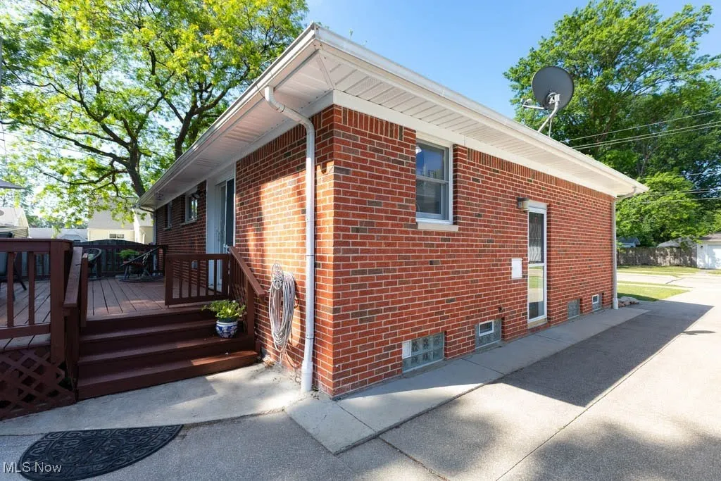 View of property exterior with brick siding and a wooden deck