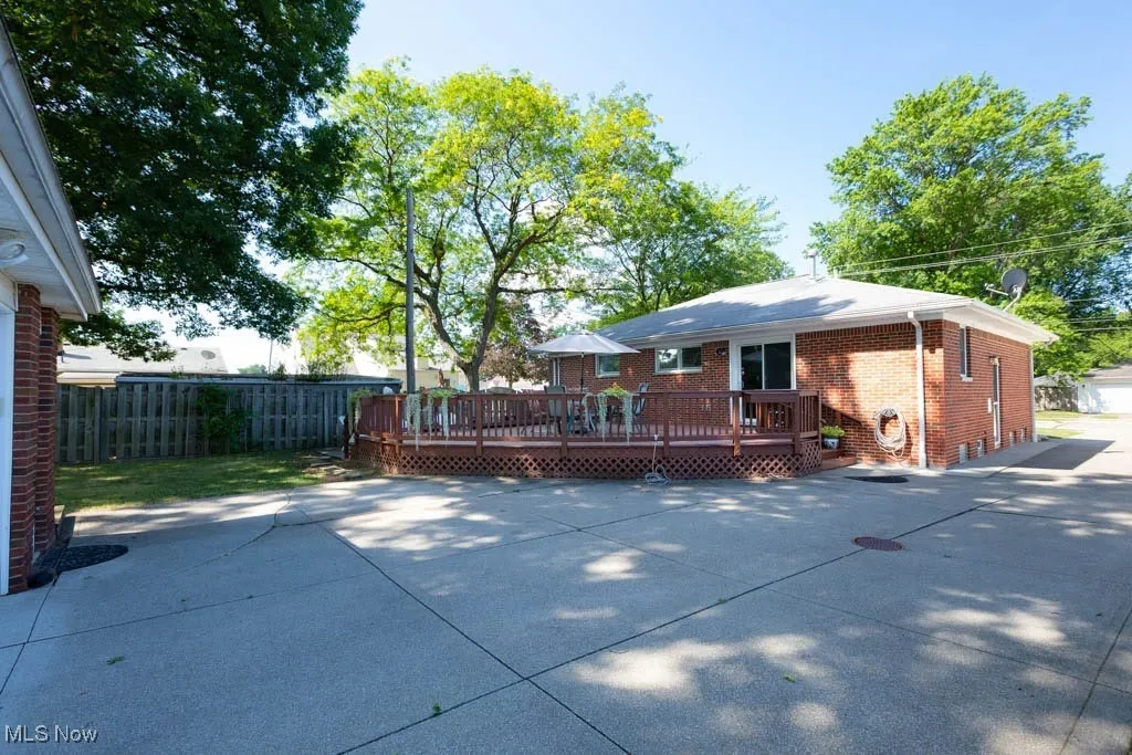 Rear view of property with a wooden deck, brick siding, and a patio area