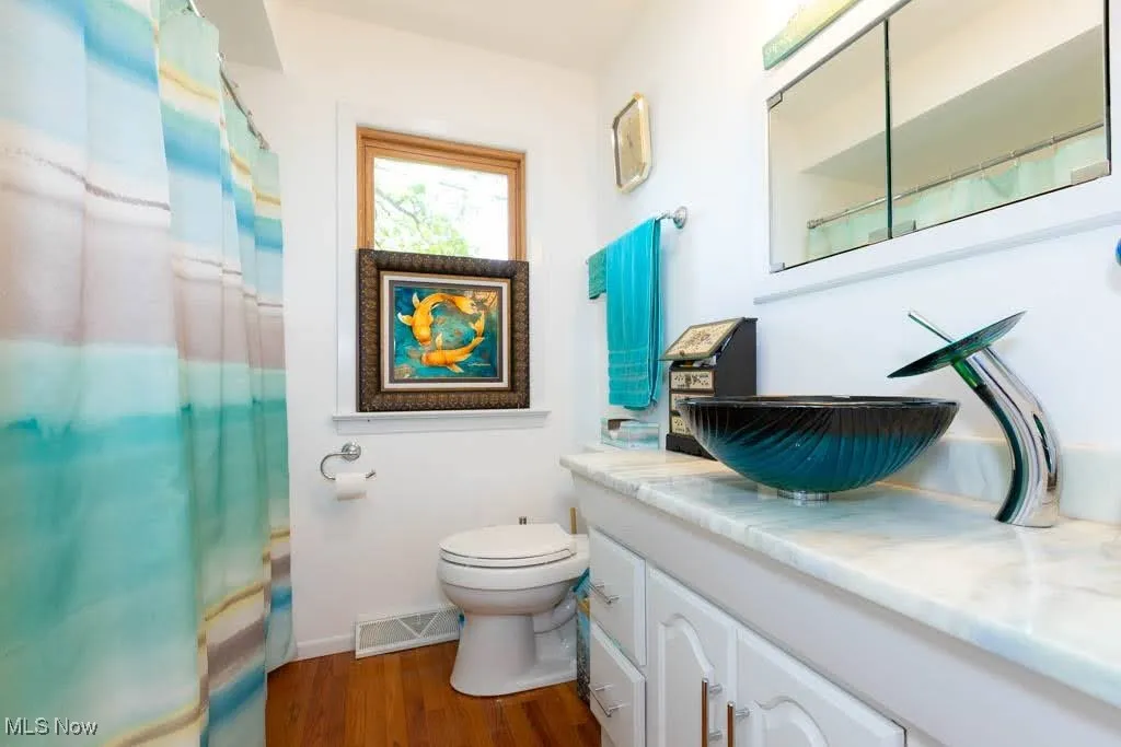 Full bath with vanity, wood finished floors, and a shower with curtain