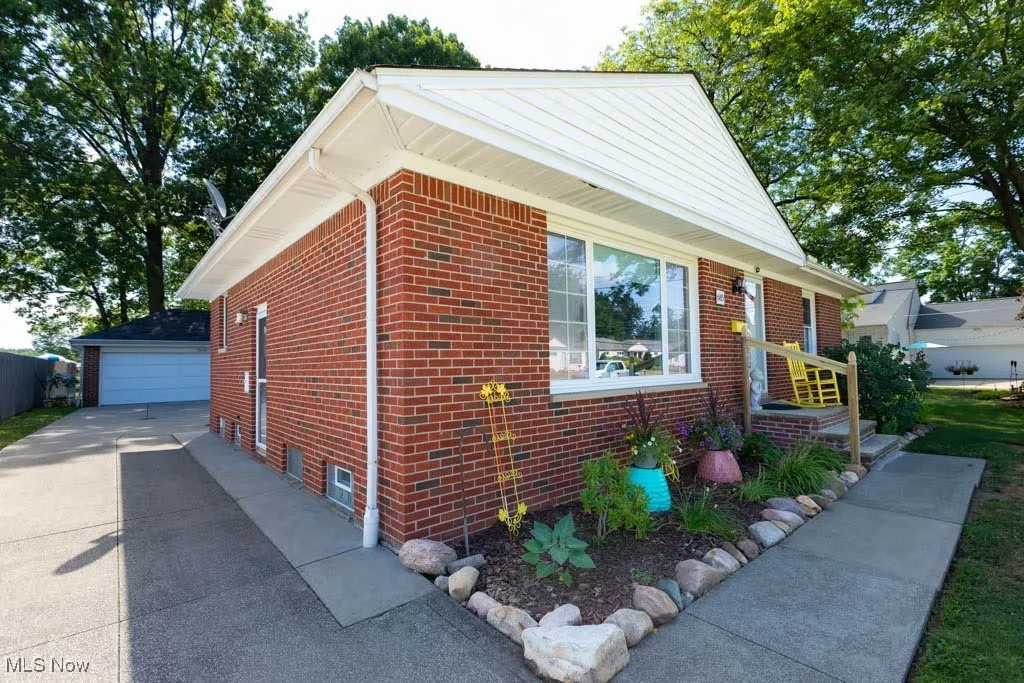 Bungalow-style house with brick siding, an outdoor structure, and a garage