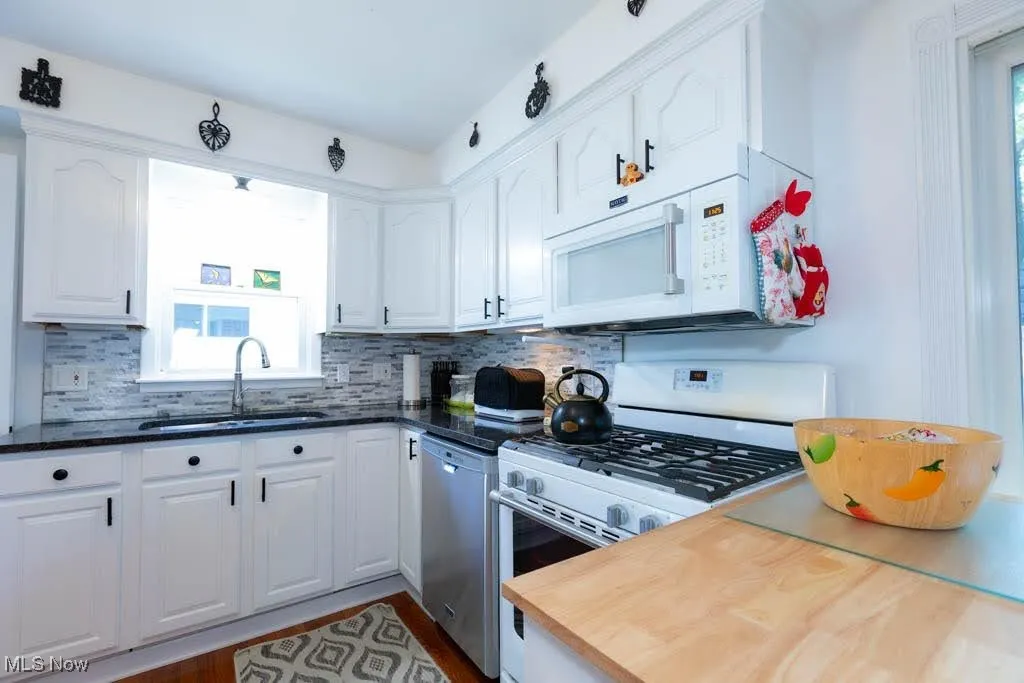 Kitchen with white appliances, plenty of natural light, and white cabinetry