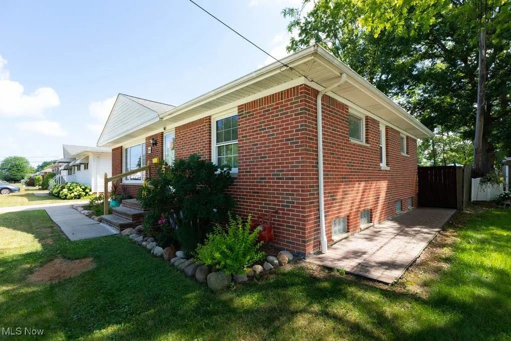 View of property exterior featuring a lawn and brick siding