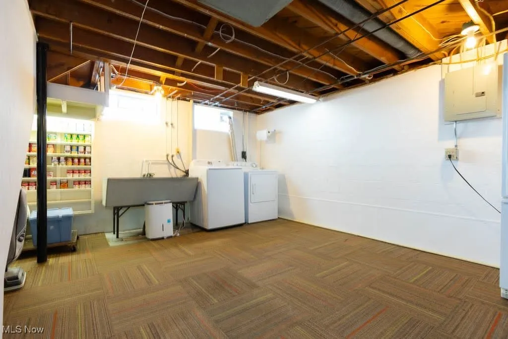 Basement featuring washer and clothes dryer, electric panel, and carpet