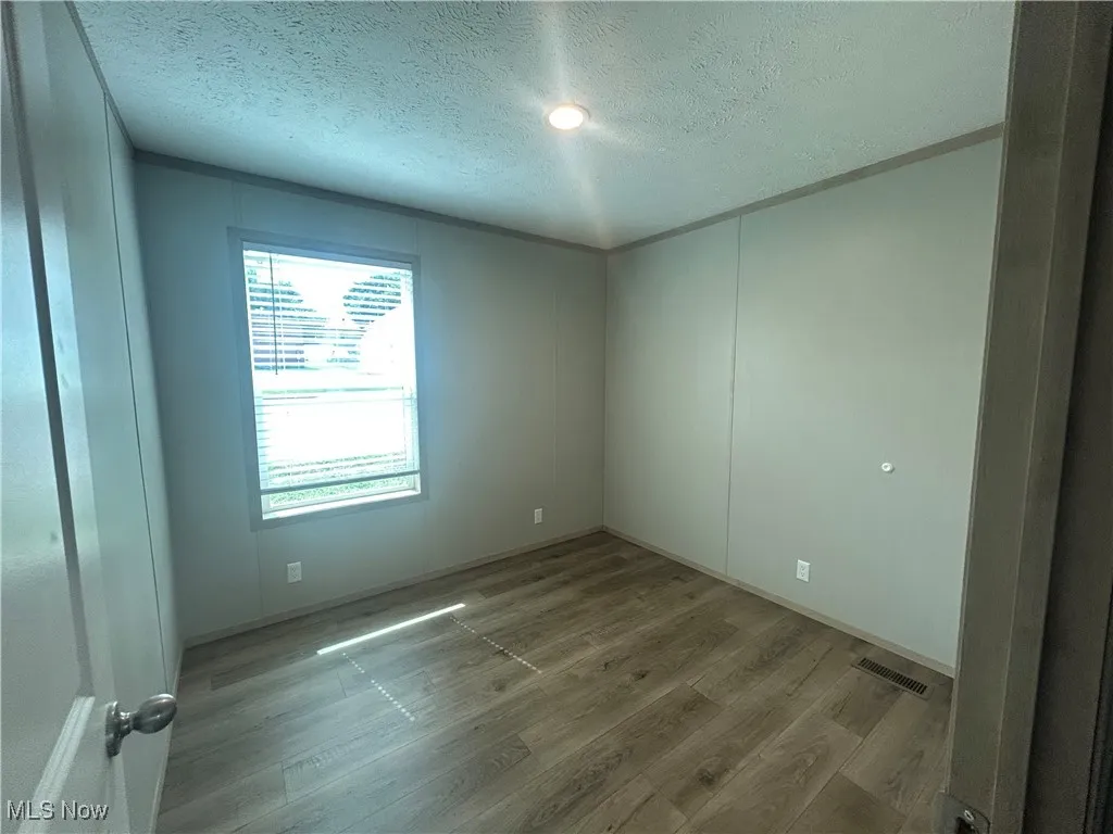 Unfurnished room featuring wood finished floors and a textured ceiling