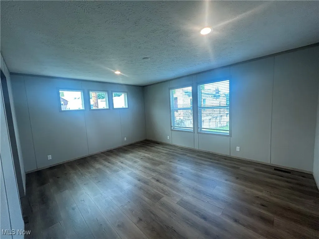 Empty room with wood finished floors, a textured ceiling, and recessed lighting