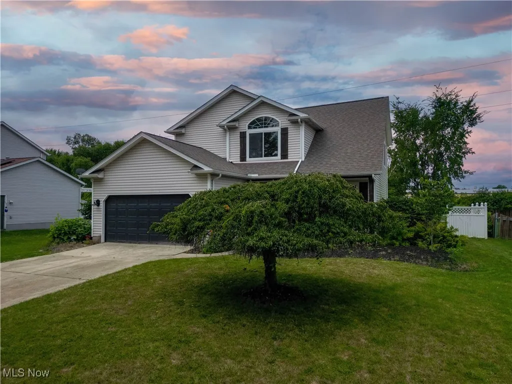 View of front of home with an attached garage, concrete driveway, and roof with shingles