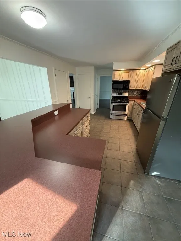 Kitchen with refrigerator, dark countertops, stove, backsplash, and dark tile patterned floors