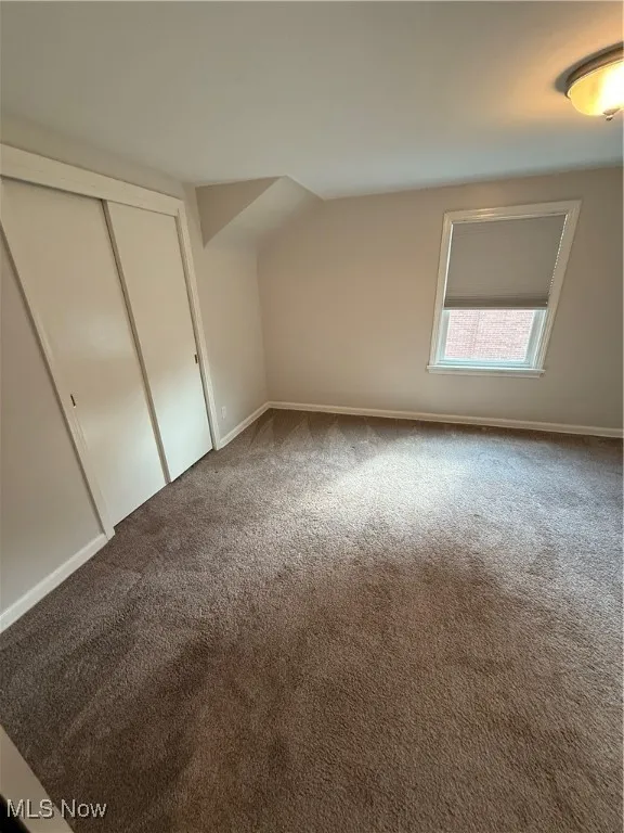 Unfurnished bedroom with carpet, lofted ceiling, and a closet