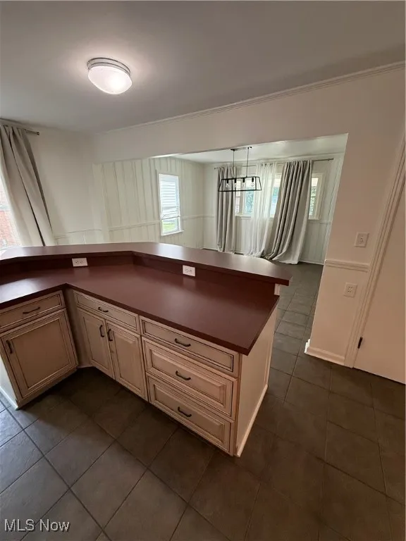 Kitchen with dark countertops, dark tile patterned flooring, plenty of natural light, and cream cabinetry